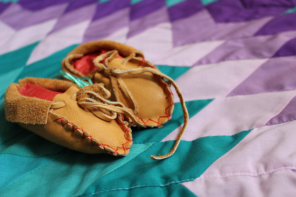baby moccasins on a teal and purple star quilt